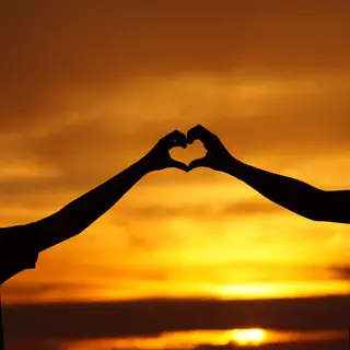 Paar-Silhouette formt Herz im Sonnenuntergang